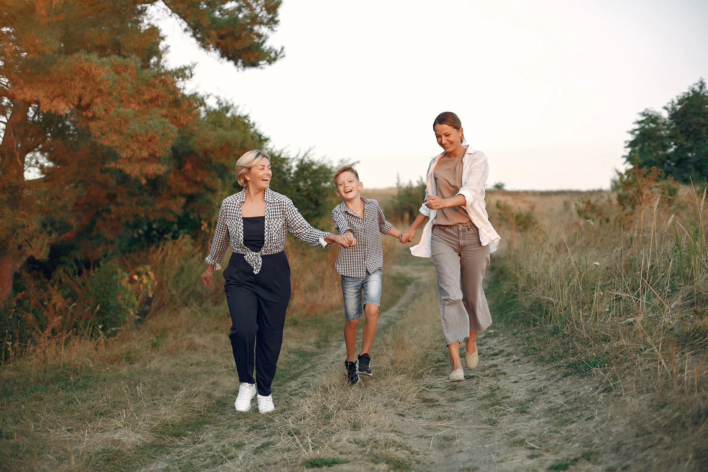 A grandmother, mother, and child walking together in the countryside